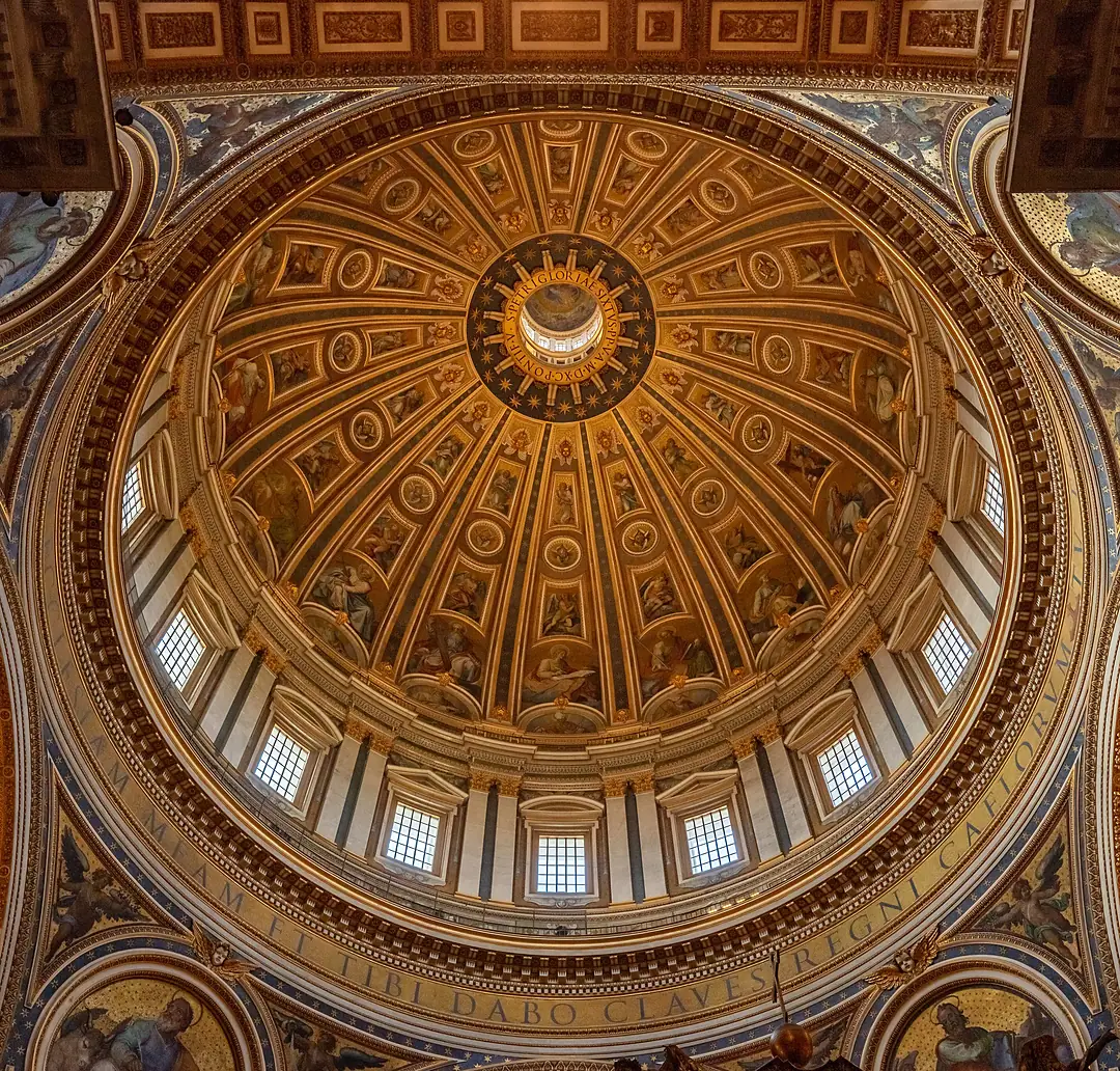 Blick senkrecht hinauf in die Kuppel des Petersdoms: goldene Rippen, sechzehn Fenster, oben die Laterne; am unteren Rand der Inschriftenring mit „ET TIBI DABO CLAVES REGNI CAELORVM“.